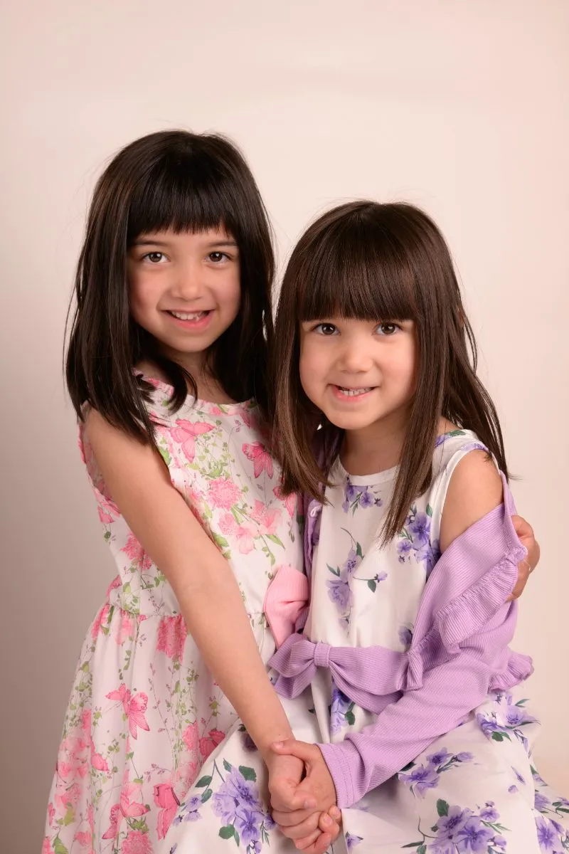 The same two sisters standing side by side, both smiling