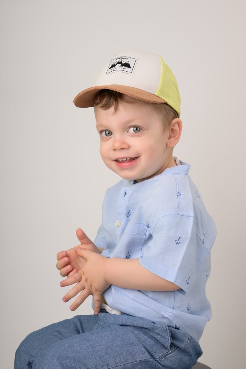 A toddler boy in a blue patterned shirt clapping his hands