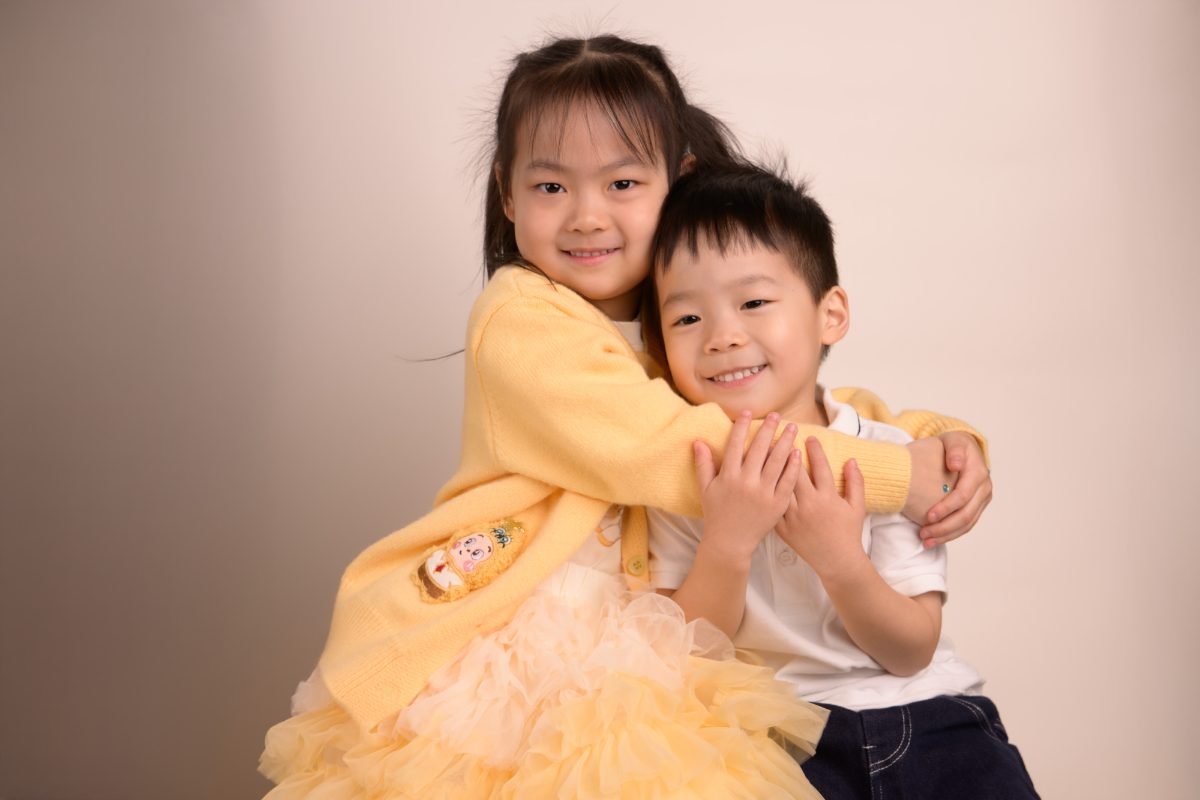 The same brother and sister hugging, both laughing