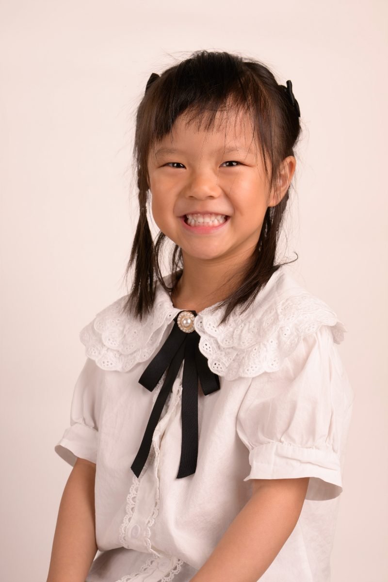 A girl in a white blouse with a black ribbon tie