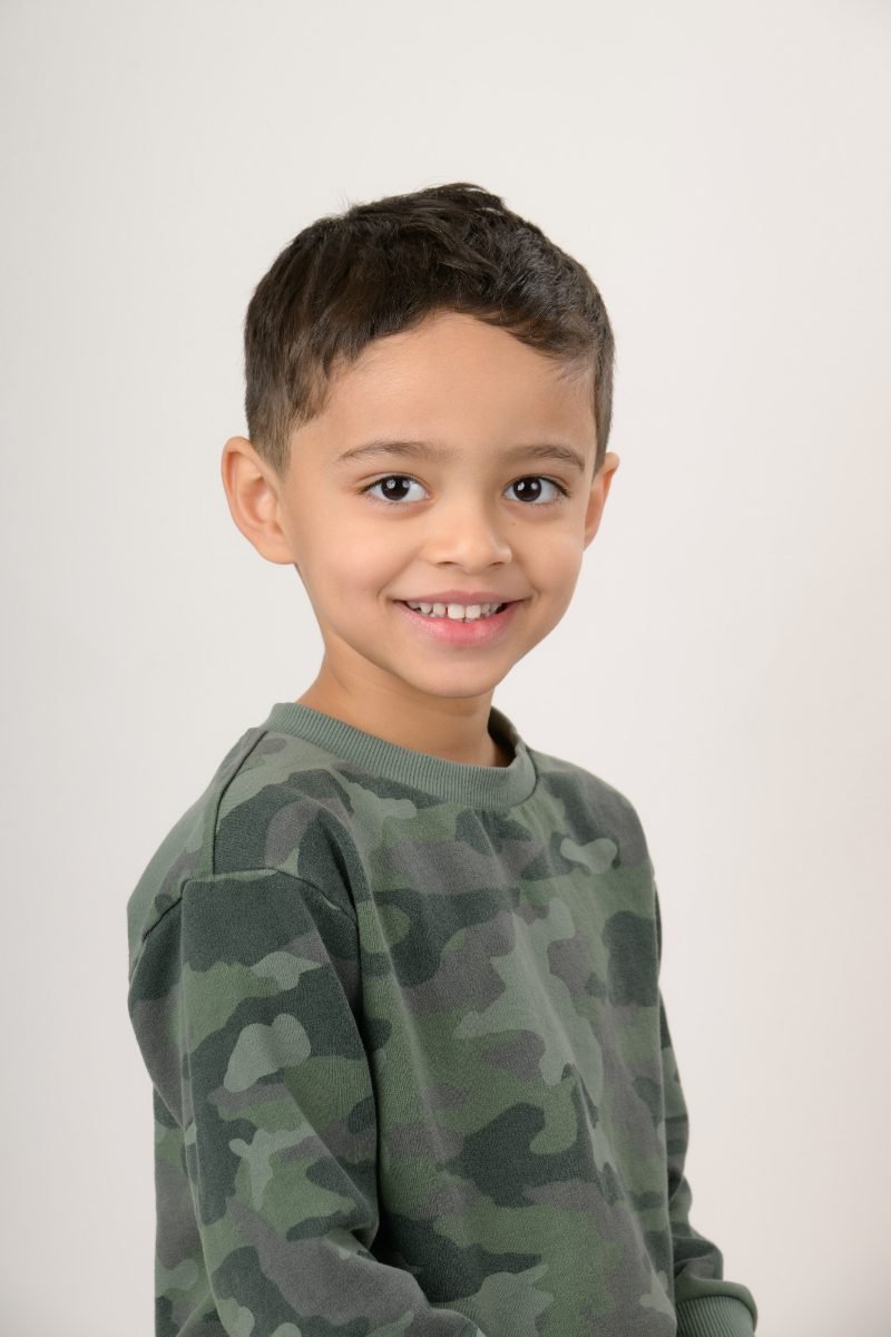 A boy in a camo long-sleeve top smiling at the camera