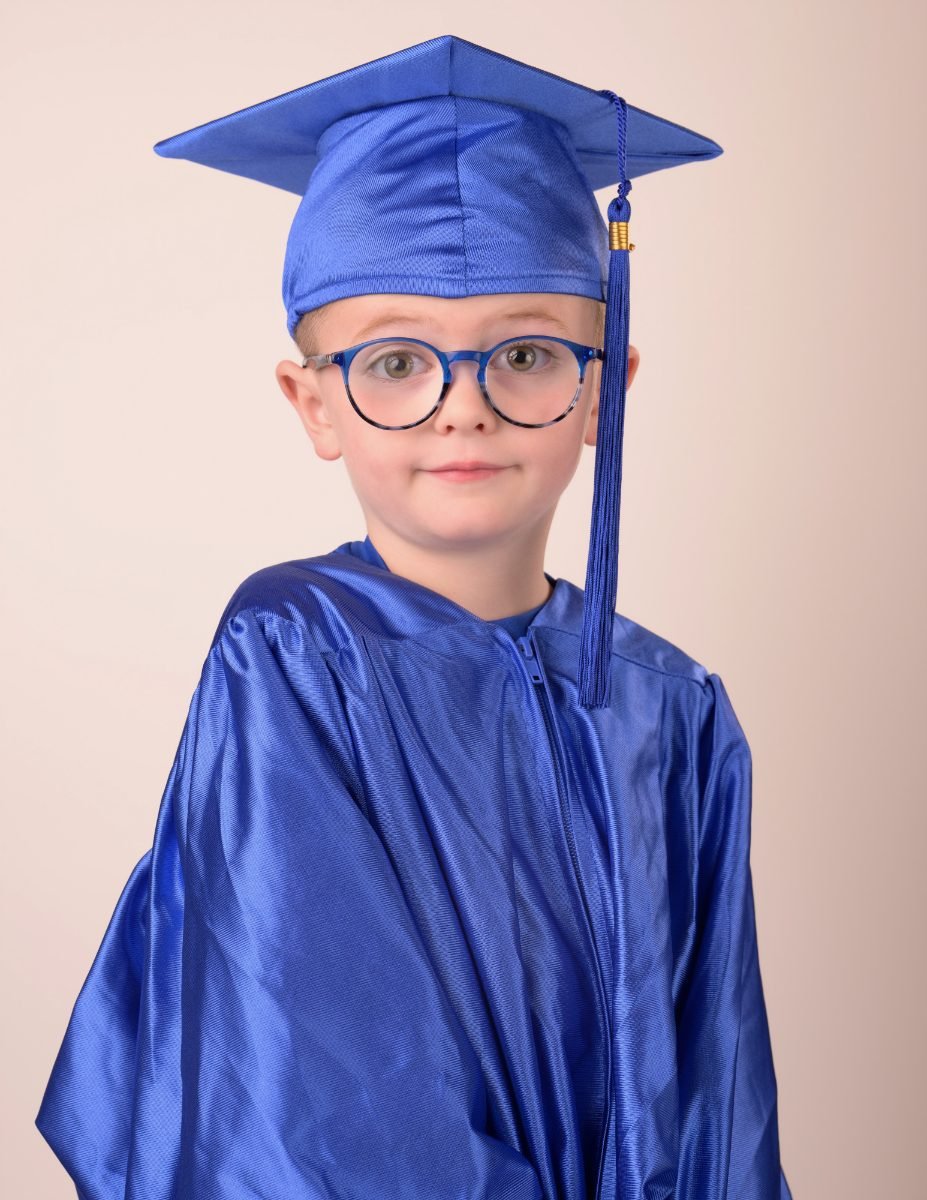 A preschool graduate in glasses and a royal blue cap and gown