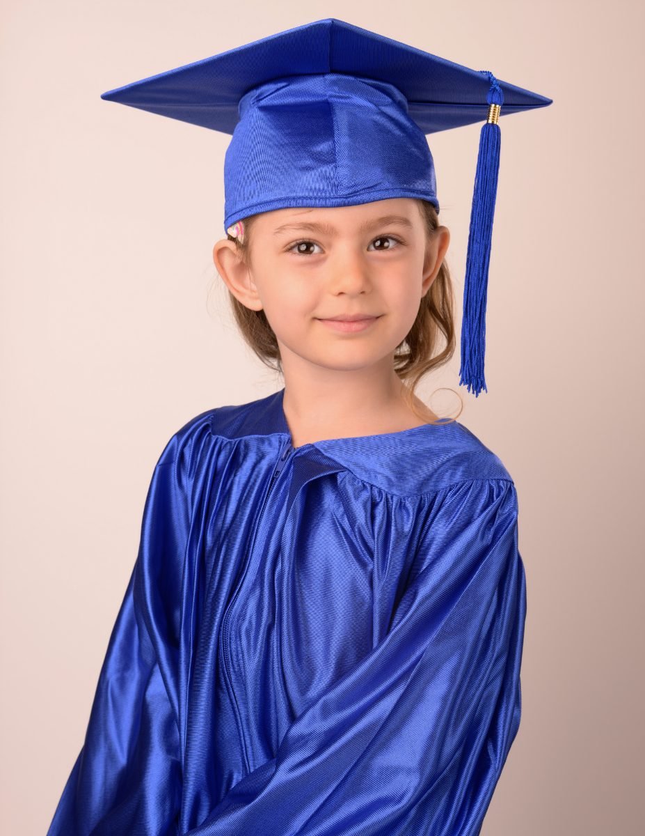 A preschool graduate in a royal blue cap and gown
