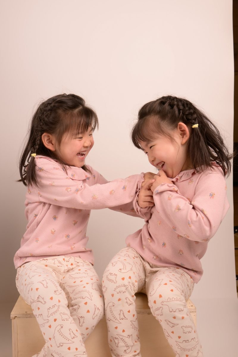 Two sisters in matching pink outfits holding hands and laughing