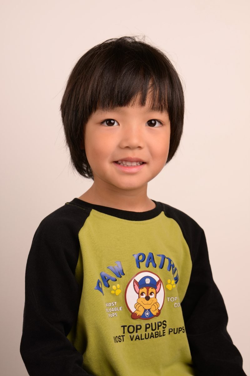 The same boy sitting upright with a wide smile