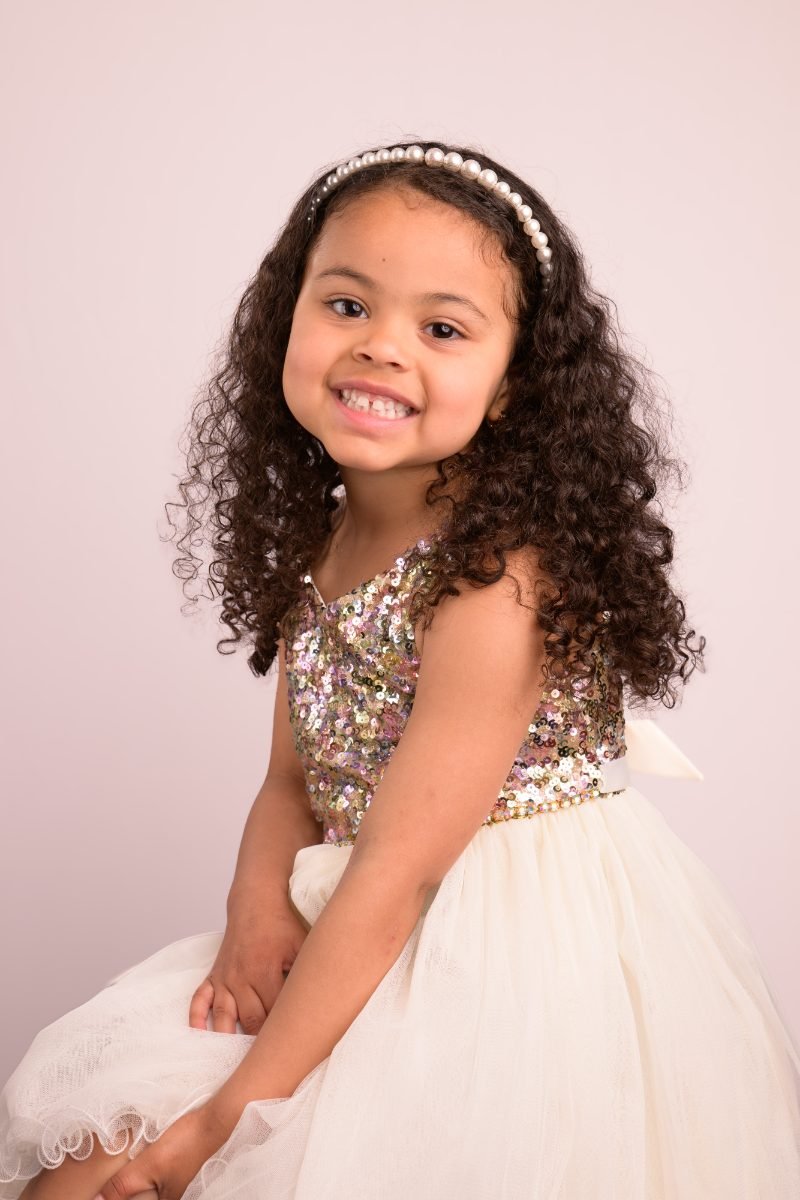 A girl in a sequin bodice and ivory tulle skirt with her head tilted