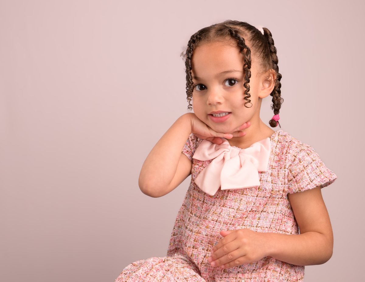 The same girl seated with her chin resting on her hand