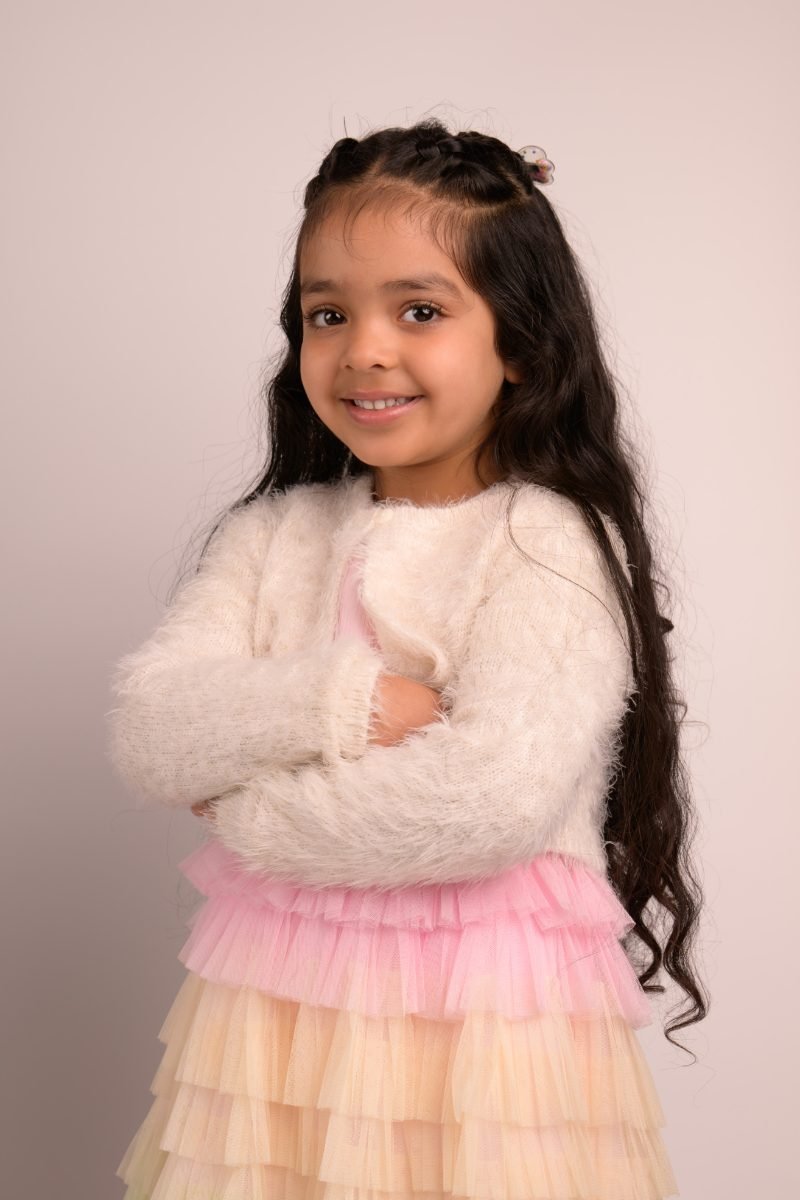 A girl in a white fluffy cardigan with her arms crossed