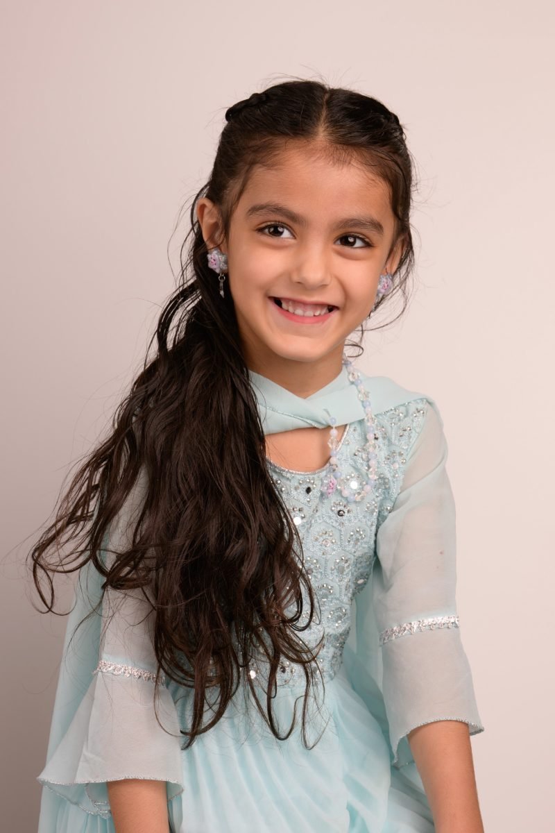 A girl with long dark hair in a teal beaded dress