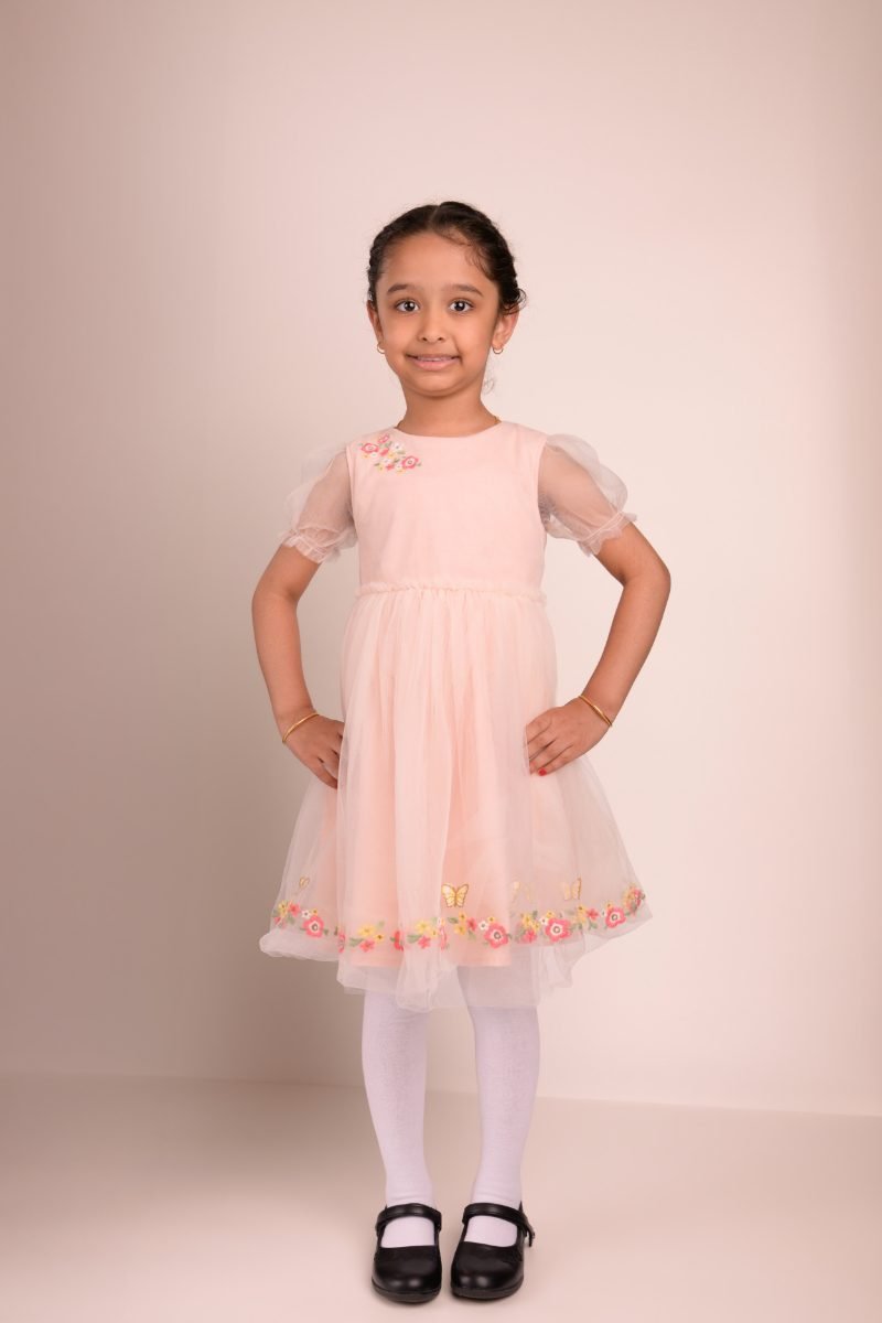 A girl in a blush tulle dress with her hands on her hips