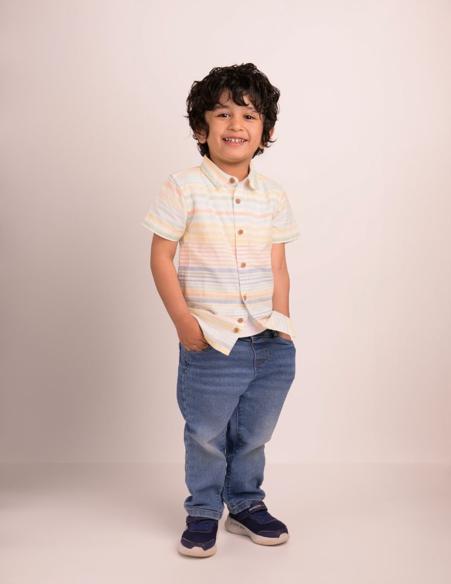 A boy in a pastel patterned shirt photographed head to toe