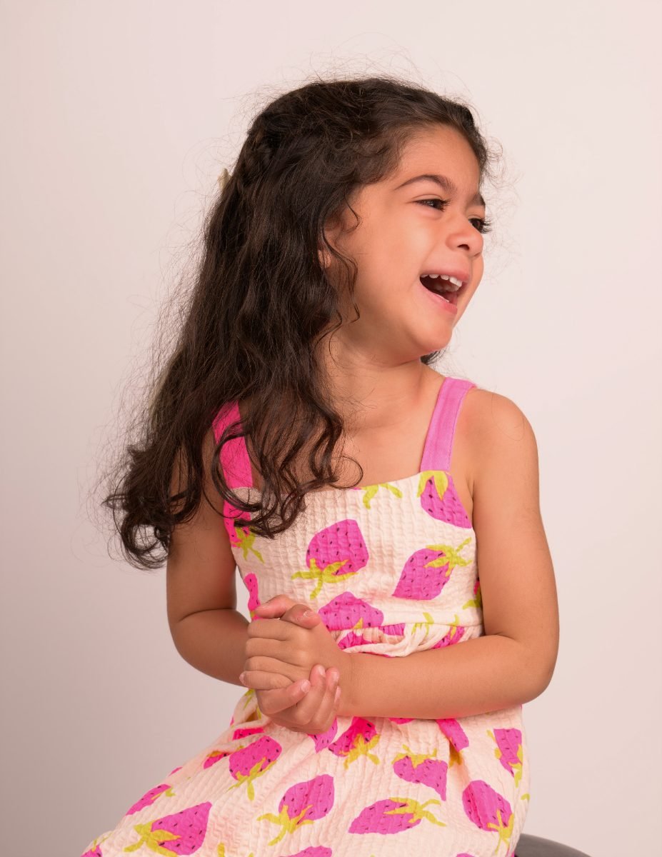 A girl with long curly hair laughing with her eyes closed