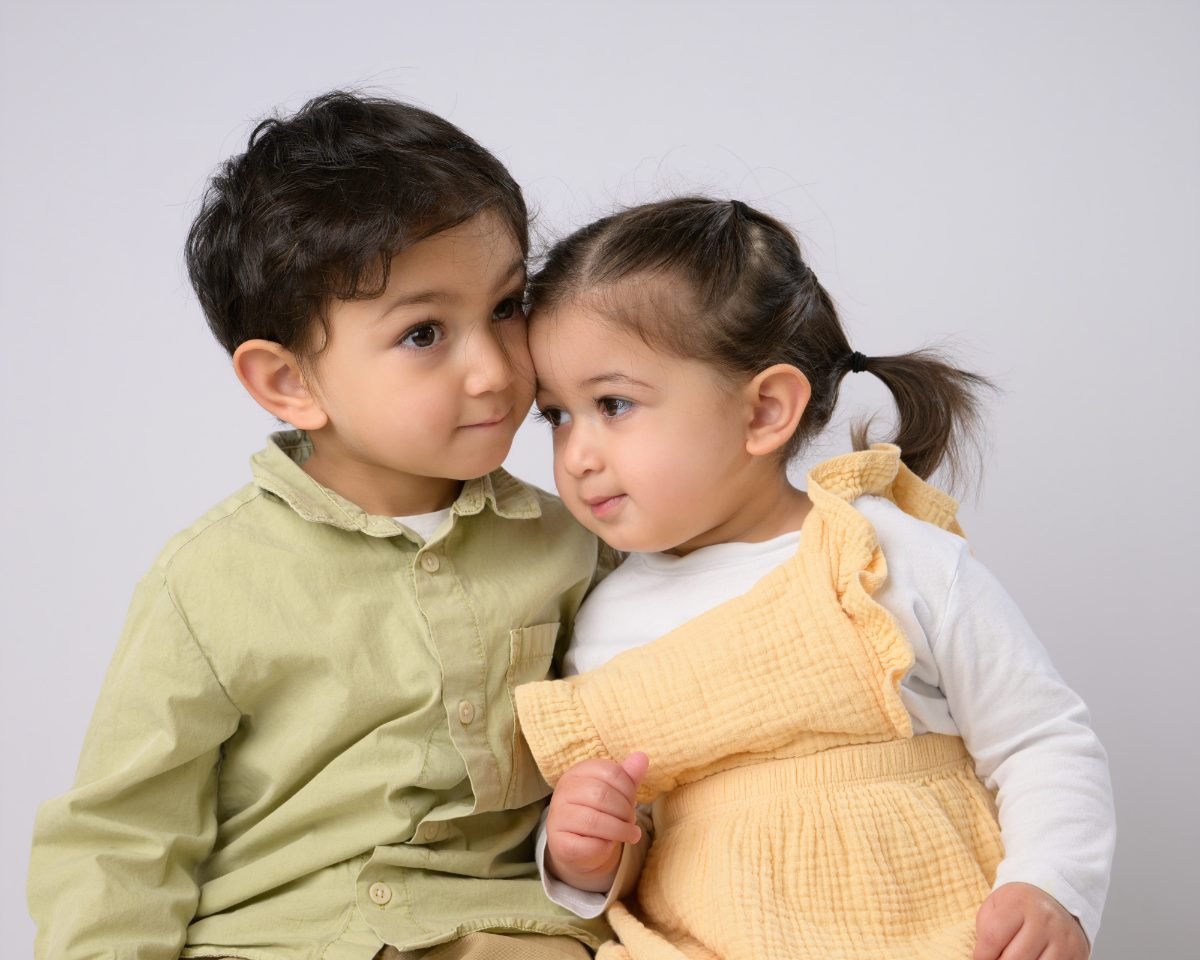 A boy leaning his forehead against his little sister’s