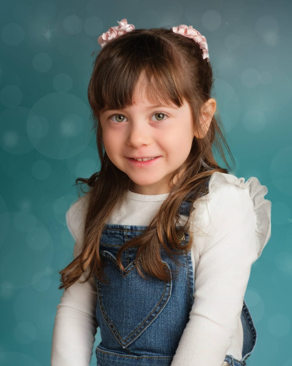 Preschool photo day portrait of a smiling girl on a teal studio backdrop