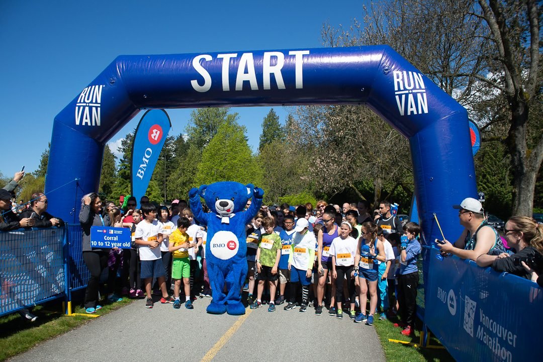 Kids lined up under the start arch at a youth run event in Vancouver