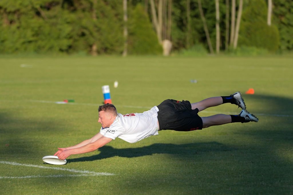Ultimate frisbee player diving for a catch during a league game in Vancouver